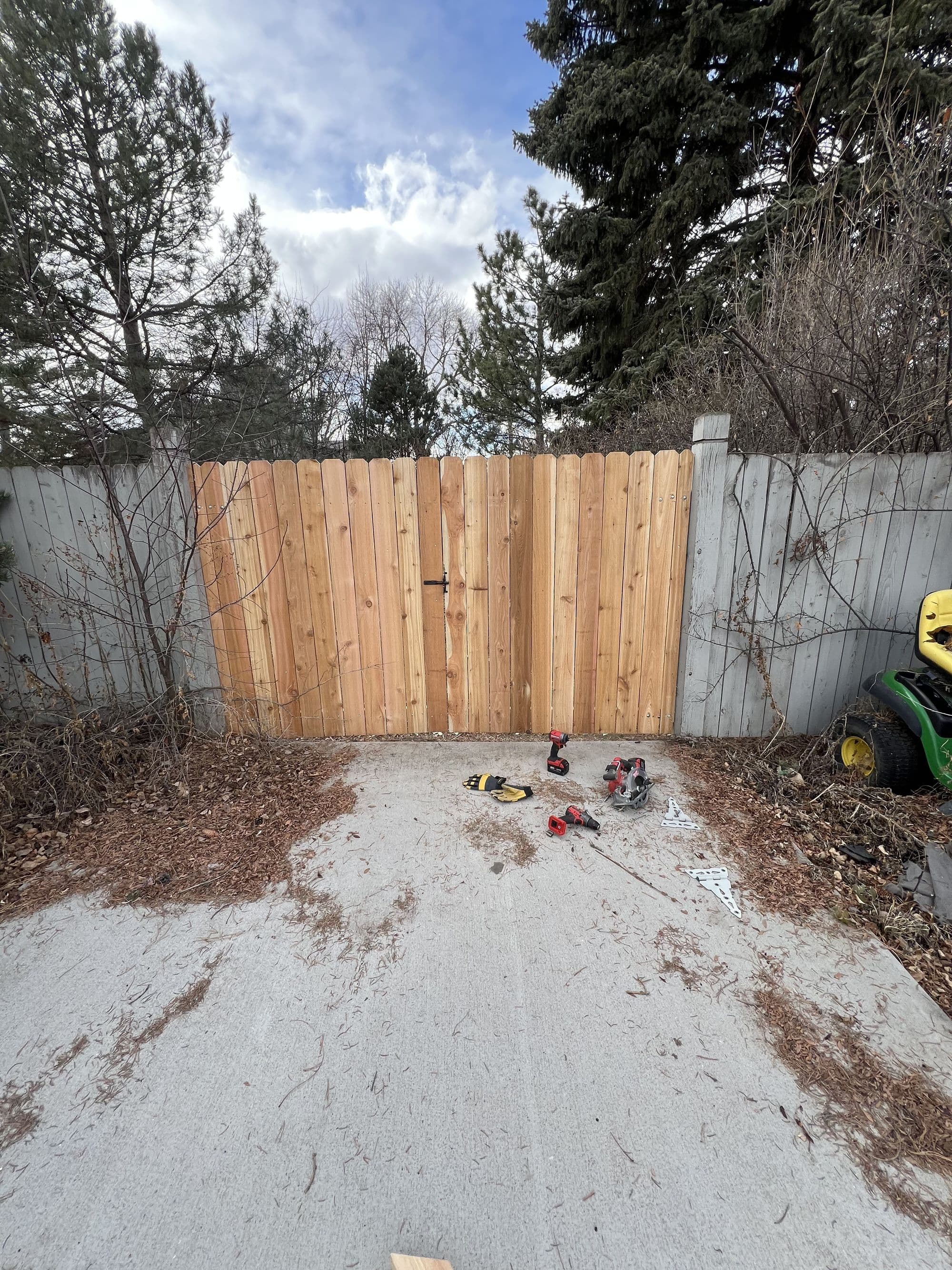 Newly repaired cedar gate section within an existing wood fence
